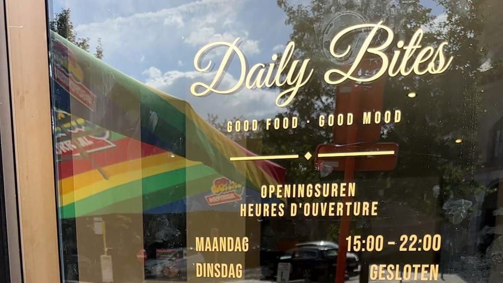 Goldene Folienbeschriftung auf der Glastür von Daily Bites in Voeren (Belgien): Logo, «Good Food · Good Mood» und die Öffnungszeiten auf Niederländisch und Französisch